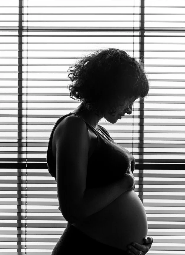 black and white image of Pregnant woman holding her baby bump