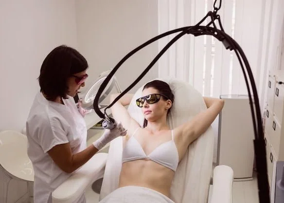 woman receiving underarm laser hair removal treatment by a female aesthetician