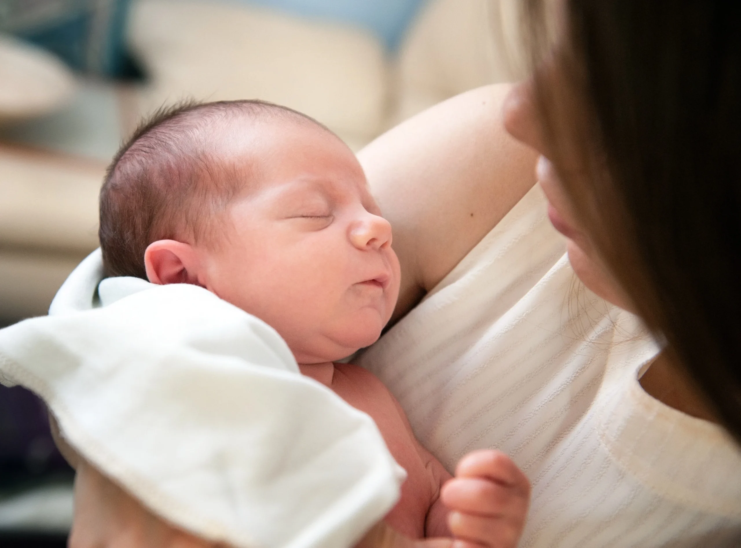 Woman caring a newborn baby wrapped in white cloth